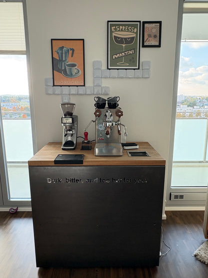 Barista-Tisch mit Siebträgermaschine und Mühle zwischen zwei Fenstern im Wohnraum